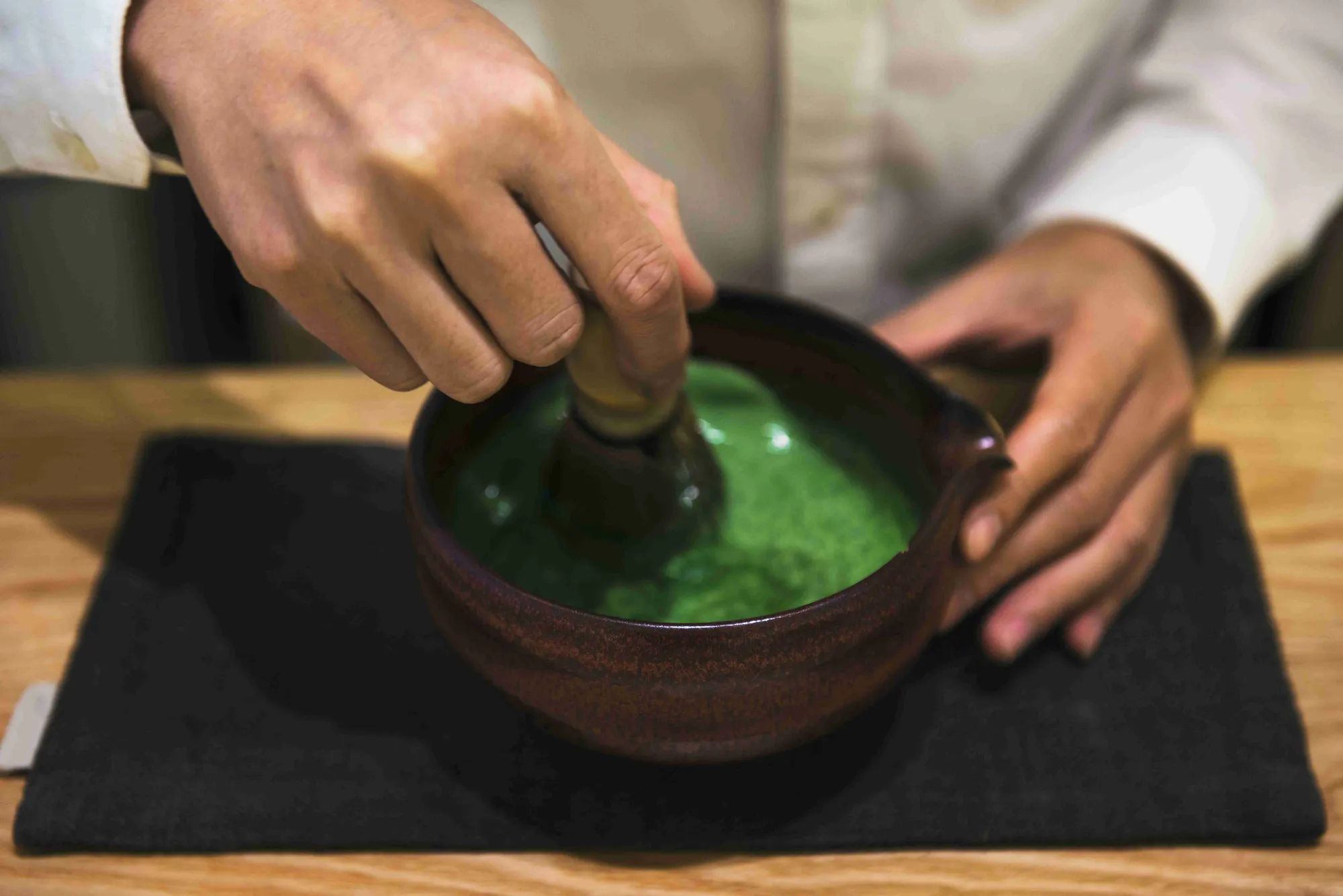 A technician grinding green neem leaf in a mortar for quality testing