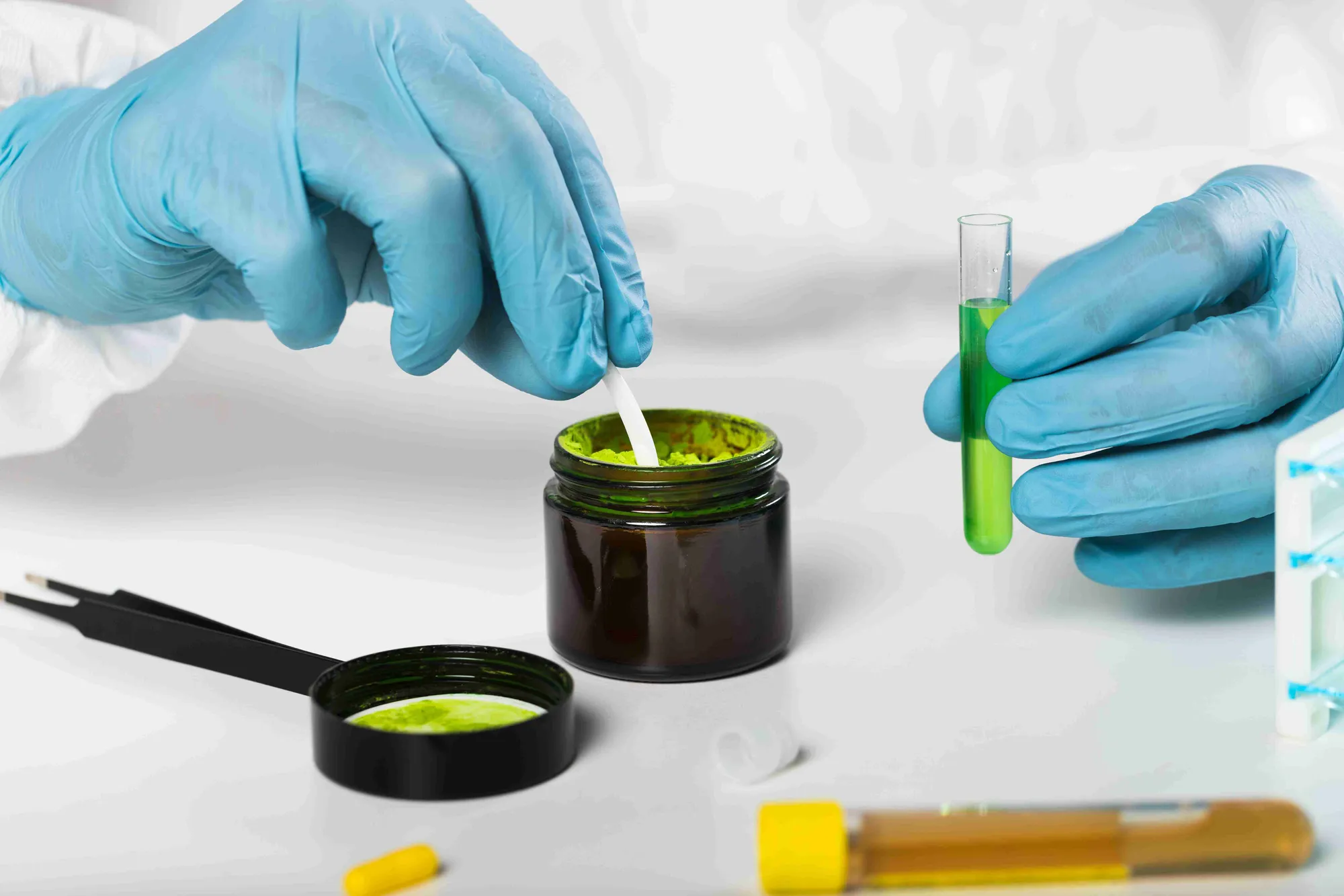 A gloved hand dropping a sample into a jar of neem extract in the lab
